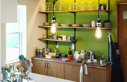 グリーンの壁がおしゃれな飾り棚のあるキッチン